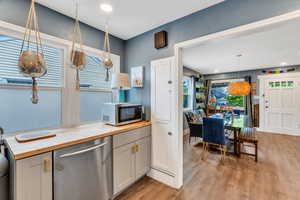 Kitchen with wood counters, stainless steel appliances, light wood-style floors, and hanging light fixtures
