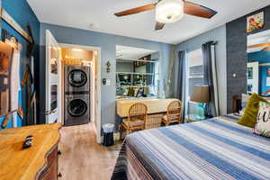 Bedroom featuring light wood-style flooring, stacked washing machine and dryer, and ceiling fan