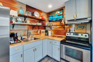 Kitchen featuring stainless steel appliances, open shelves, recessed lighting, light wood-type flooring, and wooden counters