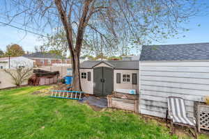 Back of property with roof with shingles and a shed