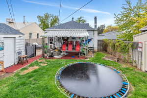 Back of house featuring a fenced backyard, roof with shingles, a trampoline, and a patio area