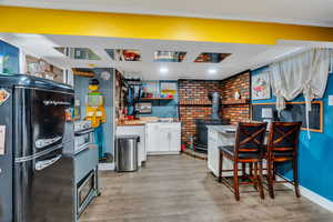 Kitchen featuring freestanding refrigerator, white cabinets, a wood stove, open shelves, and light wood-style flooring