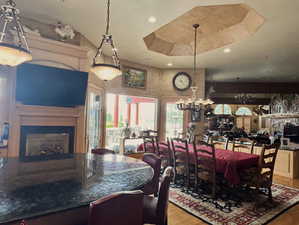 Dining room with a fireplace, a tray ceiling, light wood-style floors, and recessed lighting