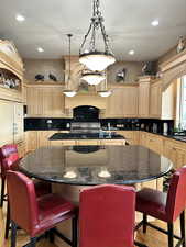 Kitchen featuring a center island with sink, light wood finish cabinets, a breakfast bar area, and dark stone countertops