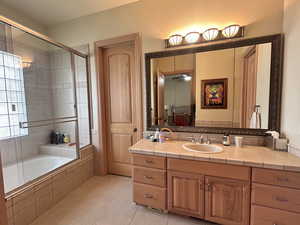 Bathroom featuring vanity, tiled shower / bath, and light tile patterned flooring