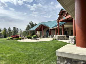 View of grassy yard featuring a patio and a fire pit