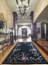 Entryway with arched walkways, light wood-type flooring, a chandelier, and a high ceiling