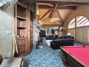 Living area featuring hanging lights, a high wooden beamed ceiling, dark carpet, a textured wall, and billiards table
