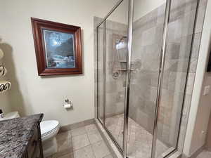 Full bath with a shower stall, vanity, and light tile patterned flooring