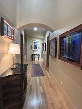 Hallway with arched walkways and light wood finished floors