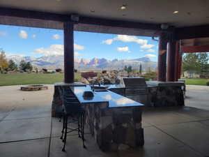 View of patio with an outdoor kitchen, a mountain view, and an outdoor fire pit