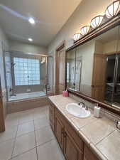 Full bath with vanity, light tile patterned flooring, and tiled shower / bath combo