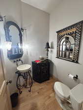 Half bathroom featuring wood finished floors and toilet