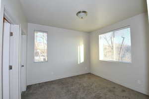 Unfurnished bedroom with dark carpet and baseboards