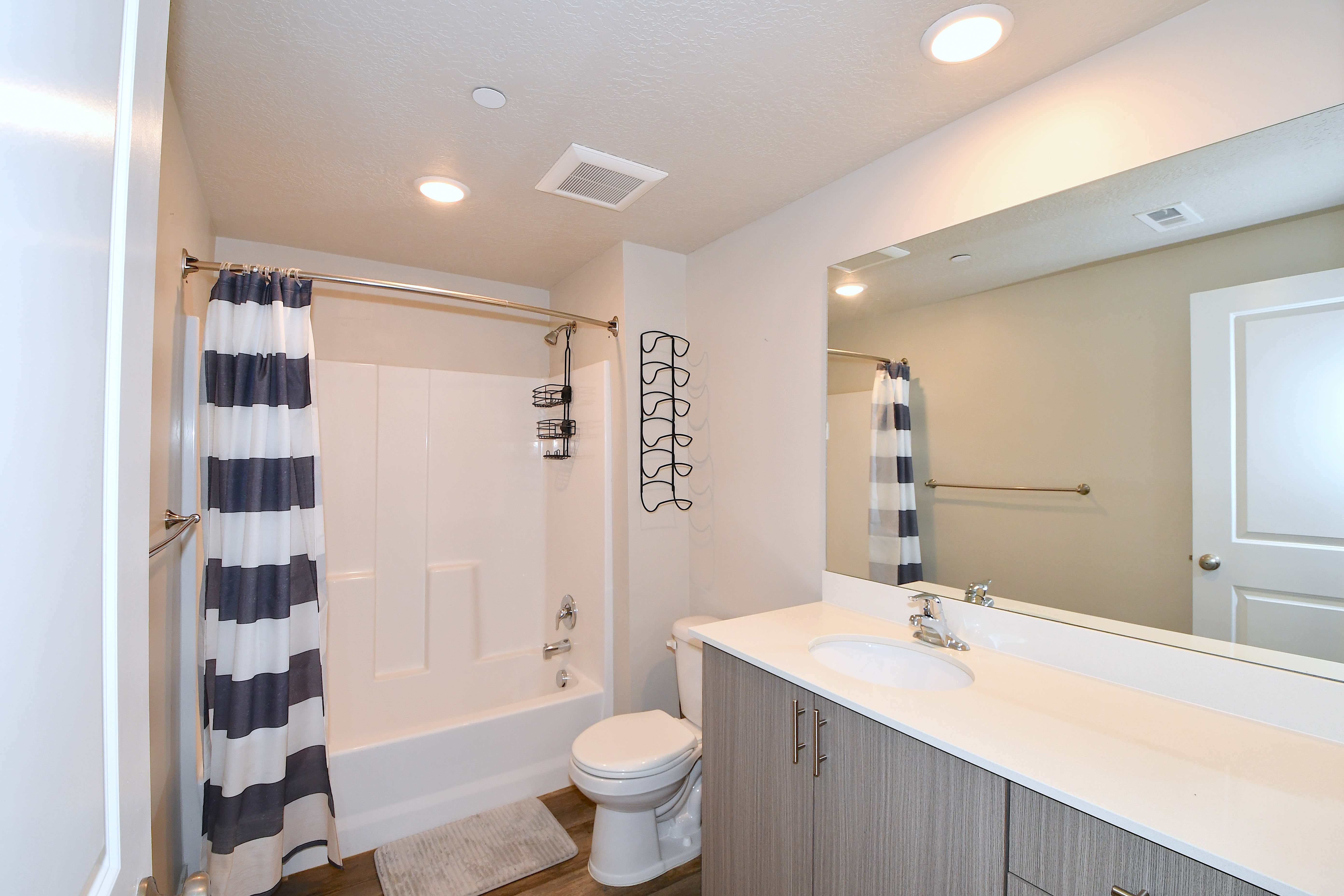 Bathroom featuring shower / bath combination with curtain, vanity, recessed lighting, and dark wood-type flooring