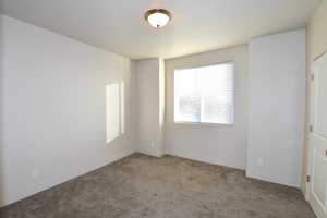 Carpeted spare room featuring baseboards