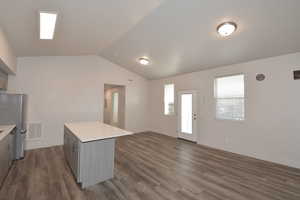 Kitchen featuring light countertops, open floor plan, dark wood-type flooring, gray cabinets, and freestanding refrigerator