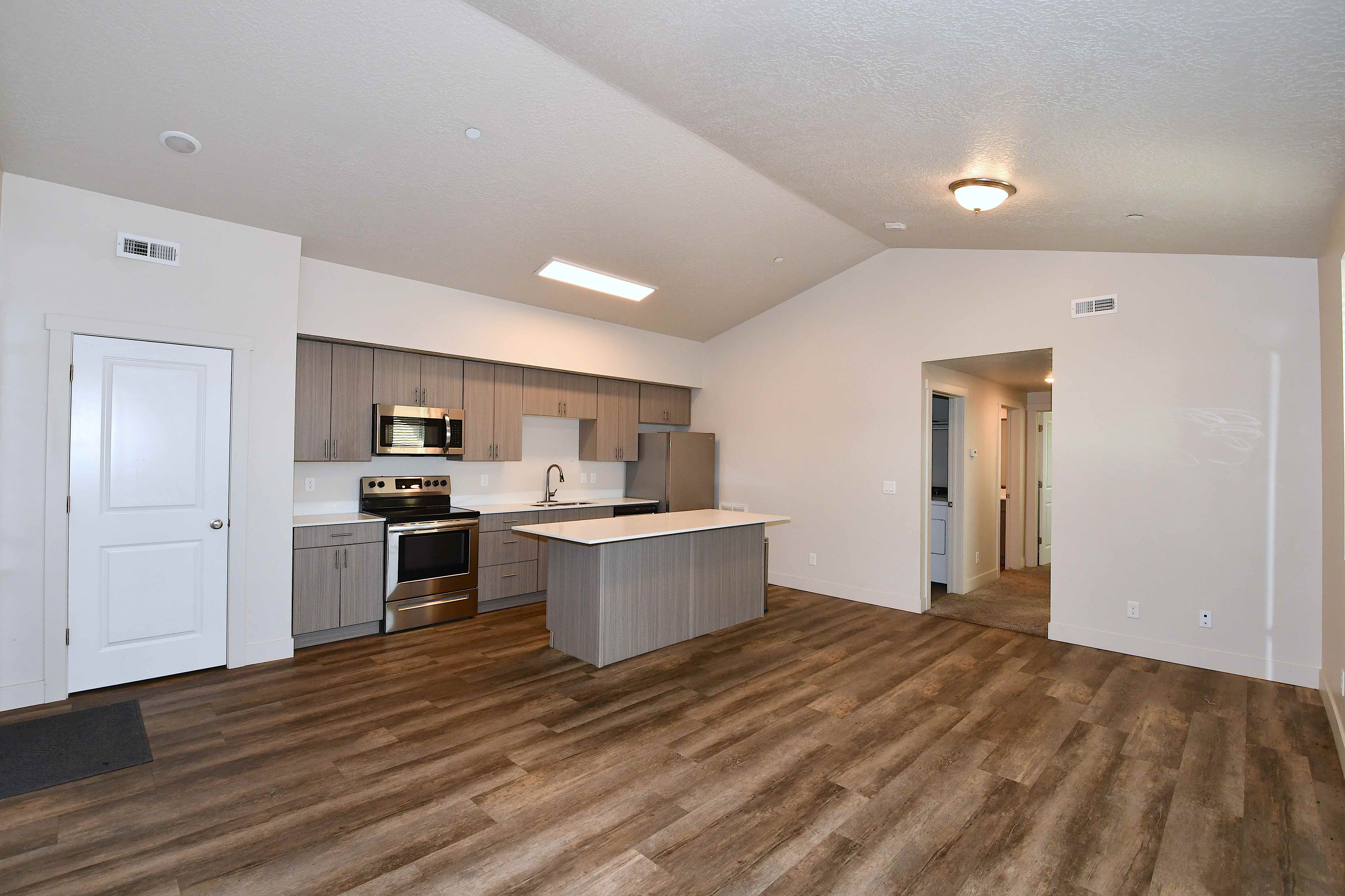 Kitchen featuring light countertops, stainless steel appliances, dark wood-style flooring, a kitchen island, and open floor plan