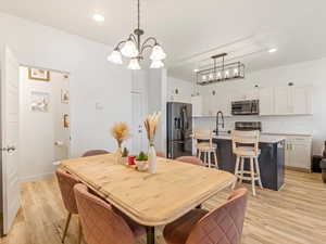 Dining room with suspended lighting and light wood-style flooring