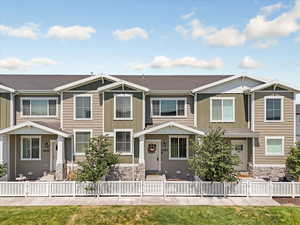 Craftsman-style house featuring board and batten siding, stone siding, a fenced front yard, and a shingled roof