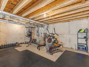 Workout area with concrete flooring, heating unit, and electric panel