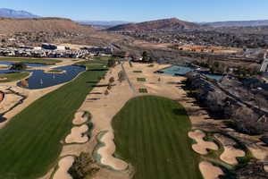 View of property location featuring a golf club, a water and mountain view, and nearby suburban area