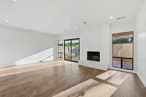 Unfurnished living room with wood finish floors and a brick fireplace