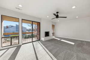 Unfurnished living room with carpet floors, ceiling fan, a fireplace, and recessed lighting