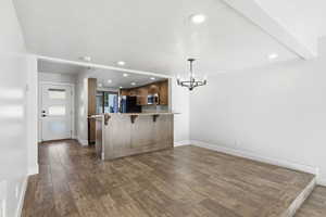 Kitchen featuring a breakfast bar, suspended lighting, dark wood-type flooring, a peninsula, and a textured ceiling