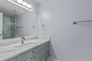 Full bath with vanity and a marble finish shower