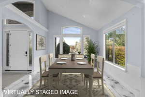 Dining room featuring arched walkways, healthy amount of natural light, vaulted ceiling, and light marble finish flooring