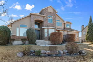 View of front facade featuring stucco siding, a front yard, and stone siding