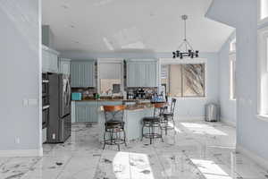 Kitchen with dark stone countertops, a kitchen island, stainless steel fridge with ice dispenser, a kitchen breakfast bar, and vaulted ceiling