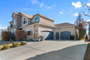 View of front of house with stucco siding, concrete driveway, stone siding, and an attached garage