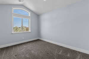 Empty room featuring dark colored carpet and baseboards