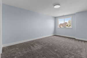 Spare room with dark carpet and baseboards