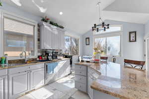 Kitchen featuring light stone counters, white cabinets, hanging lights, dishwasher, and light marble finish floors
