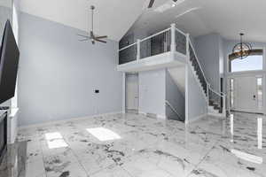 Unfurnished living room with lofted ceiling, a ceiling fan, and hanging lights