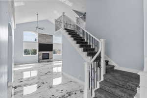 Staircase featuring a high ceiling, a premium fireplace, marble finish flooring, and a ceiling fan