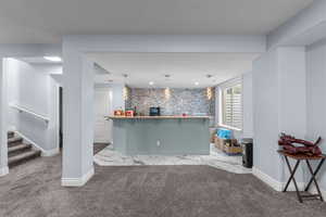 Bar featuring carpet flooring, hanging light fixtures, and an accent wall