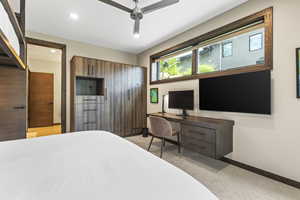 Bedroom with light colored carpet, ceiling fan, recessed lighting, and built in study area
