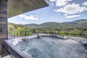 Deck featuring a patio area, a mountain view, and a hot tub