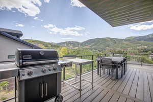 Wooden terrace featuring area for grilling, outdoor dining space, and a mountain view