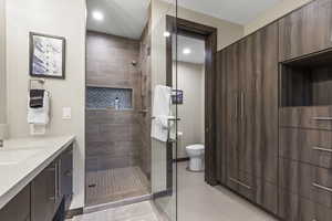 Bathroom with vanity, tiled shower, and recessed lighting