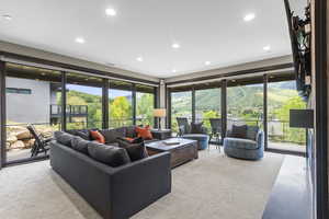 Carpeted living room with recessed lighting and plenty of natural light