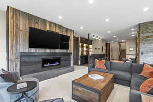 Living area with wood walls, a fireplace, light carpet, and recessed lighting