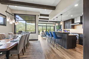 Dining space featuring light wood finished floors, beam ceiling, and a chandelier