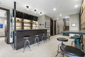 Indoor wet bar featuring dark countertops and recessed lighting
