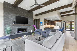 Living area featuring beamed ceiling, a large fireplace, recessed lighting, french doors, and ceiling fan