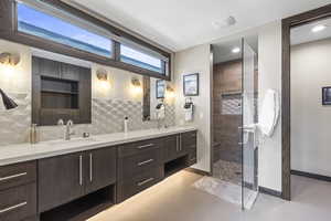 Full bathroom featuring a tile shower, double vanity, light tile patterned flooring, and backsplash